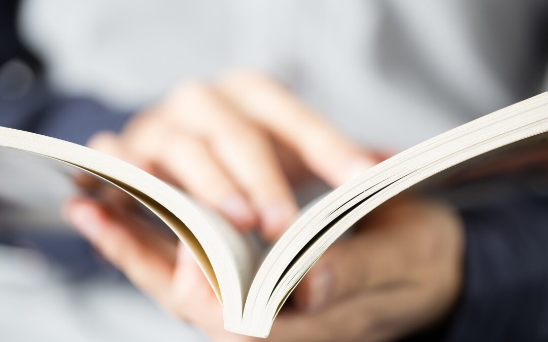 Close-up shot of hands opening and reading a paperback for page count for perfect bound books blog.